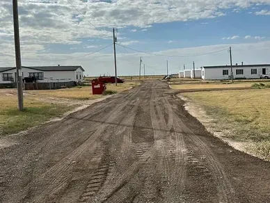A dirt road with houses in the background.